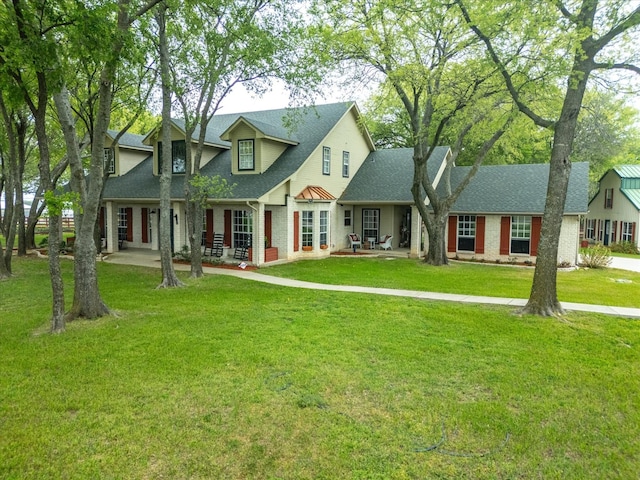 view of front of property with brick siding, a front lawn, and roof with shingles