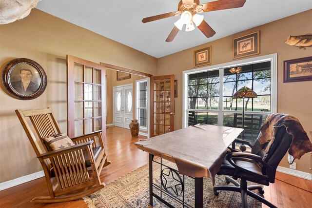 office area with light wood-style floors, baseboards, and ceiling fan