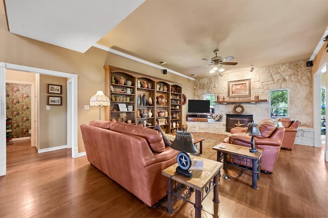 living room with baseboards, ornamental molding, a fireplace, ceiling fan, and wood finished floors