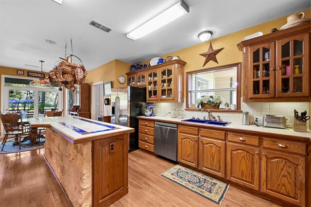 kitchen featuring brown cabinetry, a sink, visible vents, and stainless steel appliances