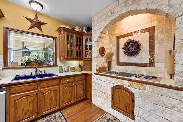 kitchen with stovetop with downdraft, light countertops, a sink, and decorative backsplash