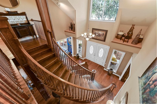 entryway featuring a high ceiling, stairway, a notable chandelier, and wood finished floors