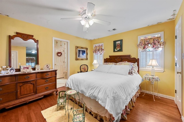 bedroom featuring dark wood-type flooring, ceiling fan, baseboards, and visible vents