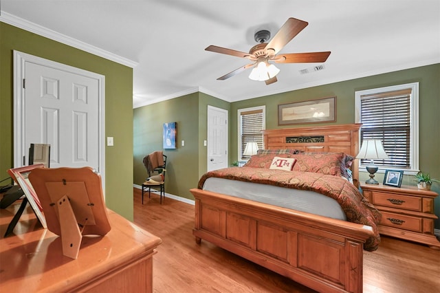 bedroom featuring baseboards, light wood-type flooring, crown molding, visible vents, and ceiling fan