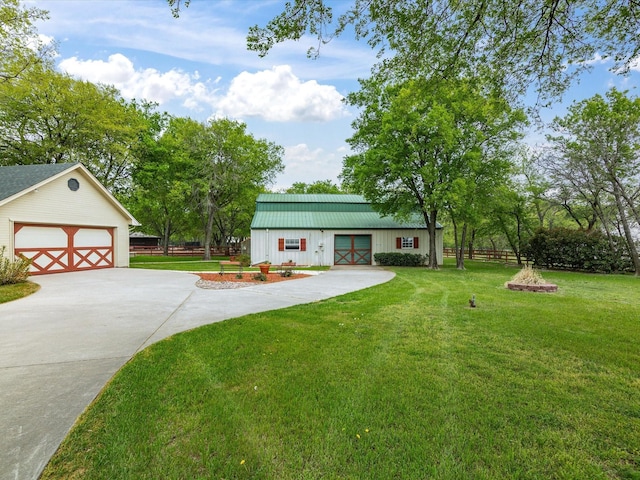 view of front of property with concrete driveway, a front yard, fence, and an outbuilding