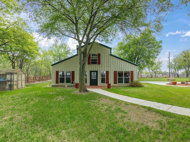 view of front of house featuring a front yard, fence, an outdoor structure, and board and batten siding