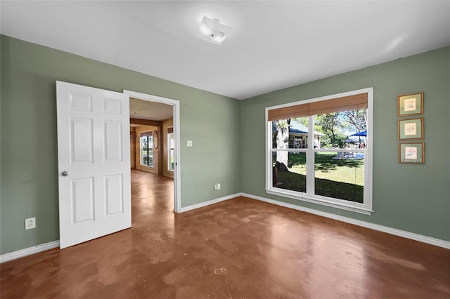 spare room featuring concrete floors and baseboards