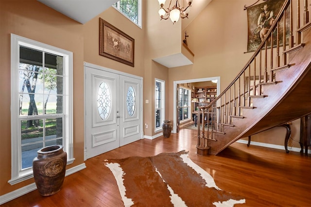 entryway featuring stairs, baseboards, an inviting chandelier, and wood finished floors
