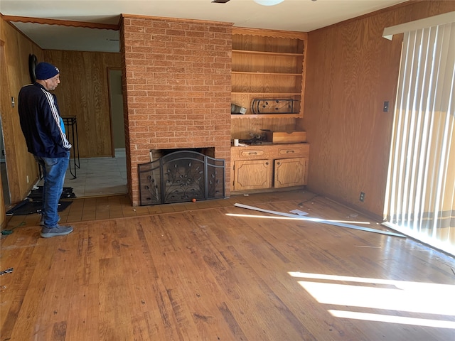 unfurnished living room with hardwood / wood-style floors, built in shelves, wood walls, and a fireplace