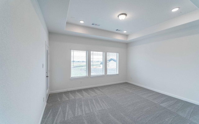 carpeted spare room with recessed lighting, a raised ceiling, visible vents, and baseboards