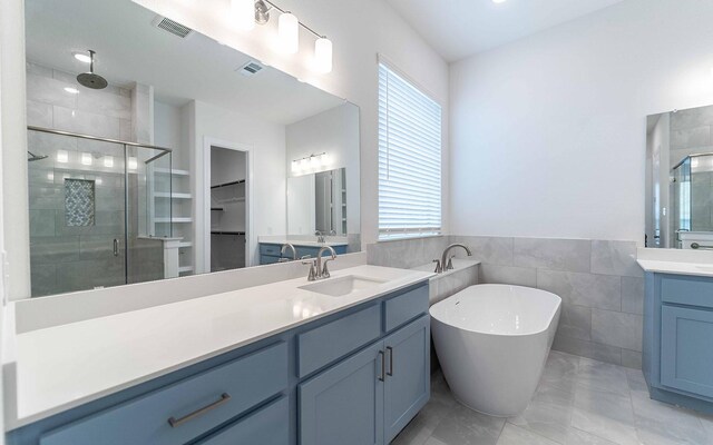 full bathroom with two vanities, a stall shower, visible vents, and a sink