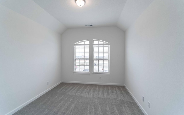 unfurnished room with carpet floors, baseboards, visible vents, and lofted ceiling