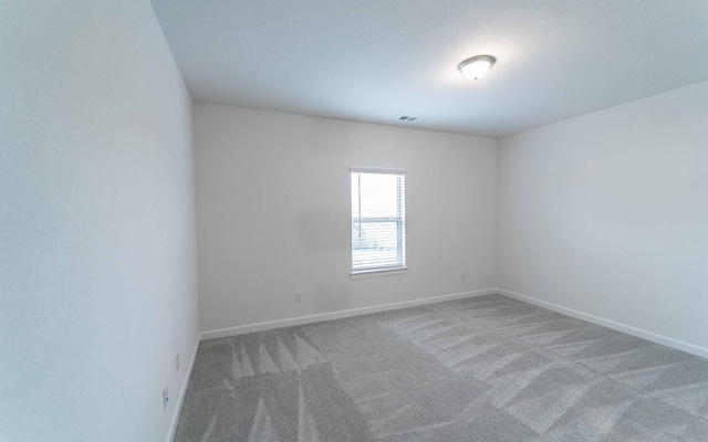 empty room featuring carpet flooring, visible vents, and baseboards