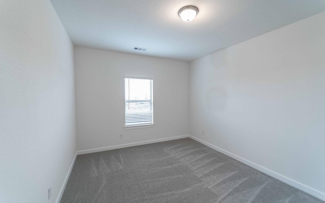 spare room featuring carpet flooring, visible vents, and baseboards