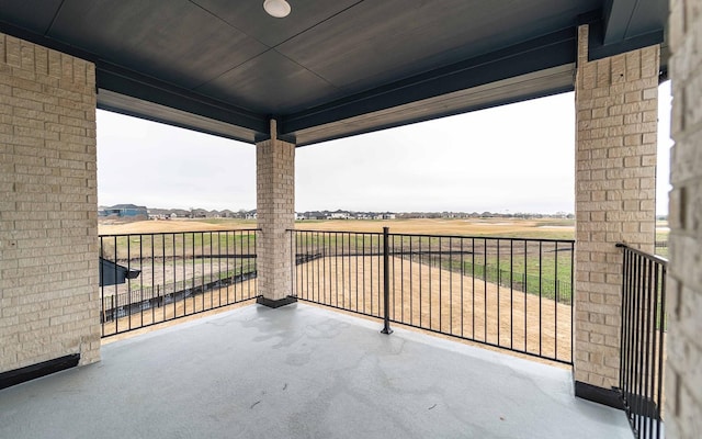 view of patio with a rural view and a balcony