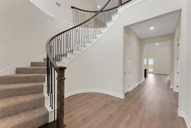 stairs featuring a towering ceiling and wood-type flooring