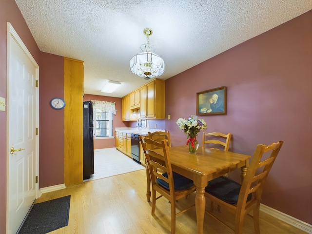 dining room with a chandelier, a textured ceiling, and light wood-type flooring