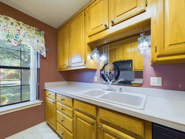 kitchen featuring a textured ceiling, decorative light fixtures, plenty of natural light, and sink