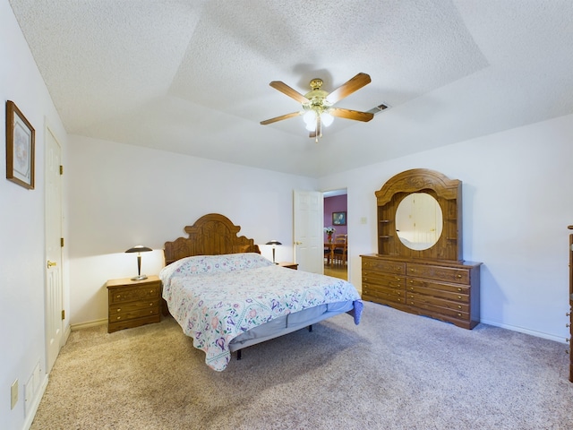 bedroom featuring ceiling fan, light colored carpet, and a textured ceiling