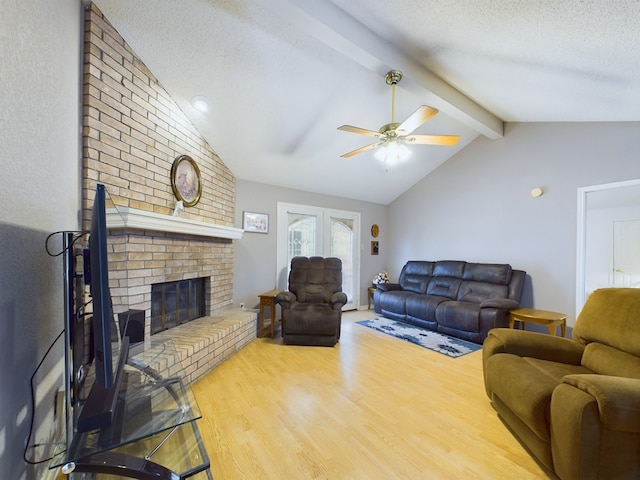 living room featuring a textured ceiling, ceiling fan, lofted ceiling with beams, hardwood / wood-style flooring, and a fireplace