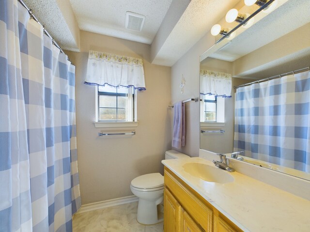 bathroom with vanity, a healthy amount of sunlight, toilet, and a textured ceiling