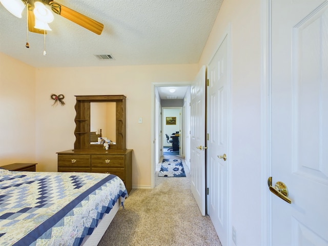 carpeted bedroom with ceiling fan and a textured ceiling