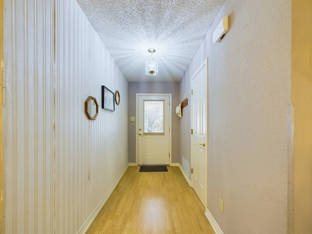 doorway featuring light wood-type flooring and a textured ceiling