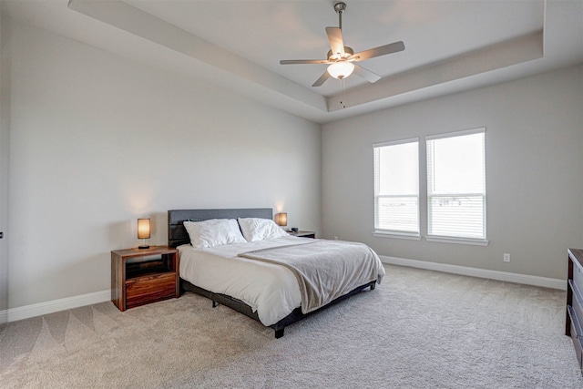 carpeted bedroom with ceiling fan and a tray ceiling