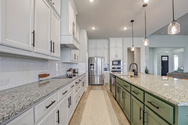 kitchen with green cabinets, sink, decorative backsplash, an island with sink, and appliances with stainless steel finishes