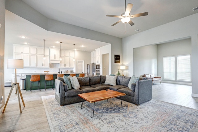 living room with ceiling fan, light hardwood / wood-style floors, and sink