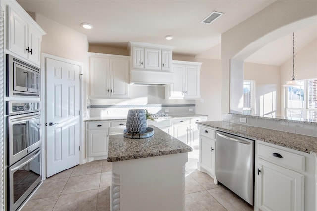 kitchen with backsplash, stainless steel appliances, pendant lighting, white cabinets, and a center island