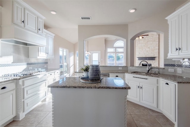 kitchen featuring white cabinetry, a center island, ceiling fan, sink, and tasteful backsplash