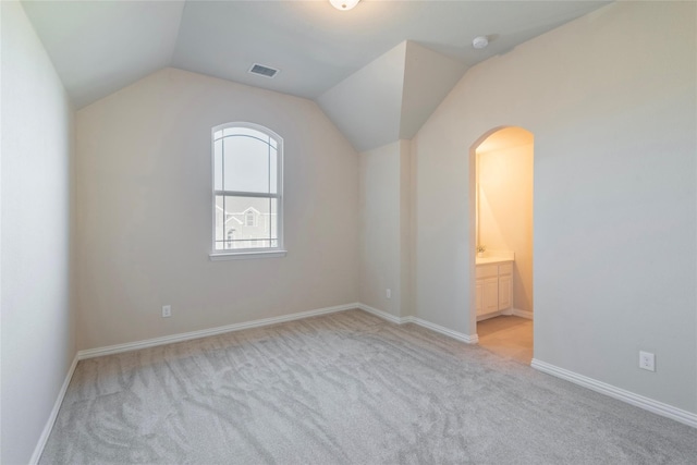 additional living space featuring light colored carpet and lofted ceiling