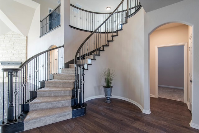 stairway with wood-type flooring and a high ceiling