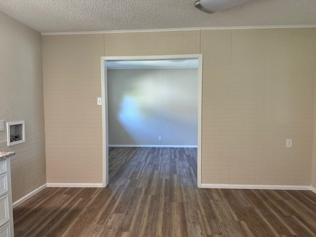 empty room featuring crown molding, dark wood-type flooring, and a textured ceiling