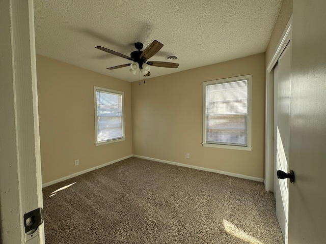 carpeted empty room featuring ceiling fan, a healthy amount of sunlight, and a textured ceiling