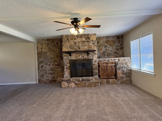 unfurnished living room featuring ceiling fan, a stone fireplace, carpet floors, and a textured ceiling