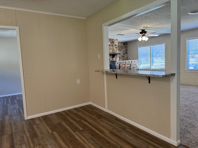 kitchen featuring ceiling fan, dark hardwood / wood-style flooring, brick wall, and a textured ceiling