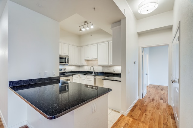 kitchen featuring kitchen peninsula, stainless steel appliances, white cabinets, and light hardwood / wood-style floors