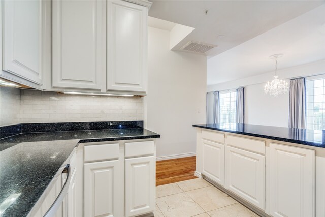 kitchen featuring white cabinetry, plenty of natural light, dark stone counters, and a notable chandelier