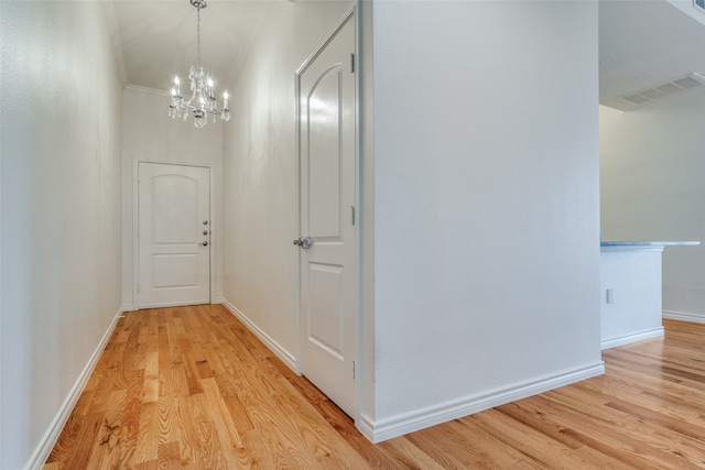 hallway with light hardwood / wood-style floors and a notable chandelier