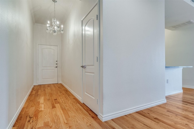 hallway with light hardwood / wood-style floors and a notable chandelier