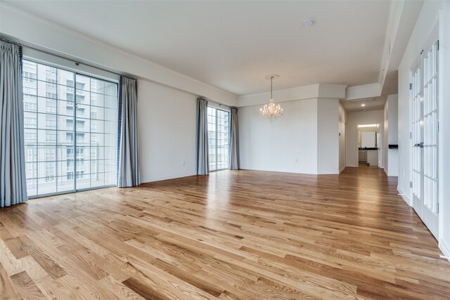 unfurnished room with an inviting chandelier, light hardwood / wood-style flooring, and ornamental molding