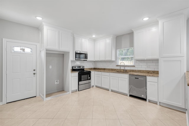 kitchen with backsplash, light stone counters, stainless steel appliances, sink, and white cabinets