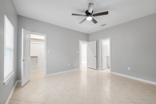 unfurnished bedroom with ceiling fan, a spacious closet, light tile patterned floors, connected bathroom, and a closet