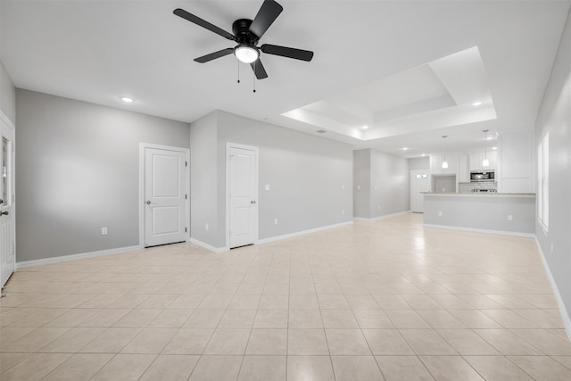 unfurnished living room featuring ceiling fan, a raised ceiling, and light tile patterned floors