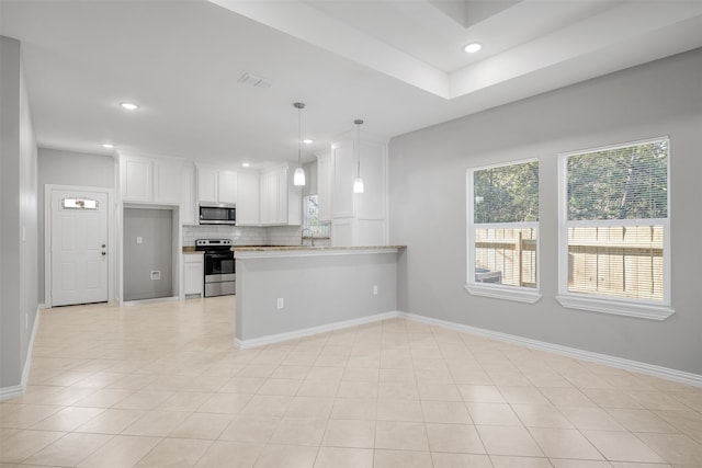 kitchen with kitchen peninsula, light stone counters, stainless steel appliances, pendant lighting, and white cabinetry