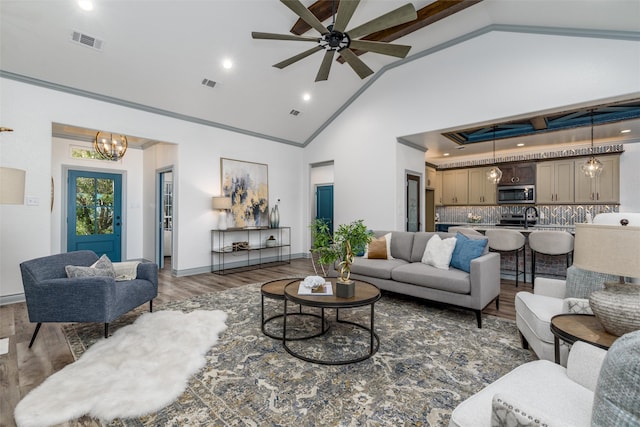 living room featuring dark hardwood / wood-style flooring, high vaulted ceiling, and ceiling fan with notable chandelier