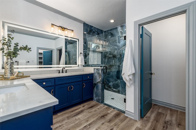 bathroom featuring a textured ceiling, vanity, crown molding, hardwood / wood-style flooring, and a shower with shower door