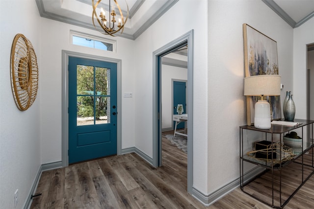 entrance foyer with dark hardwood / wood-style floors, crown molding, a tray ceiling, and a chandelier